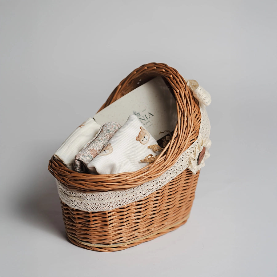 koszyczek prezentowy na baby shower z ubrankami niemowlęcymi w stylu boho - body z krótkim i długim rękawem oraz bawełniana czapeczka.