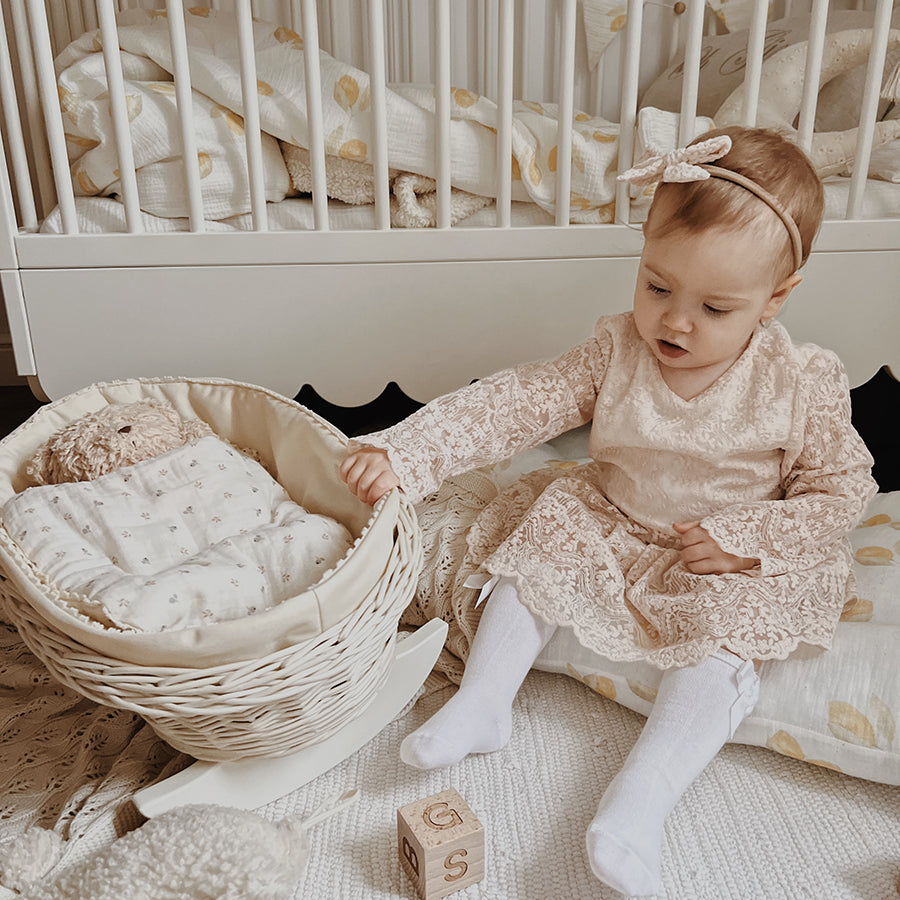 White wicker doll cradle with berry bedding