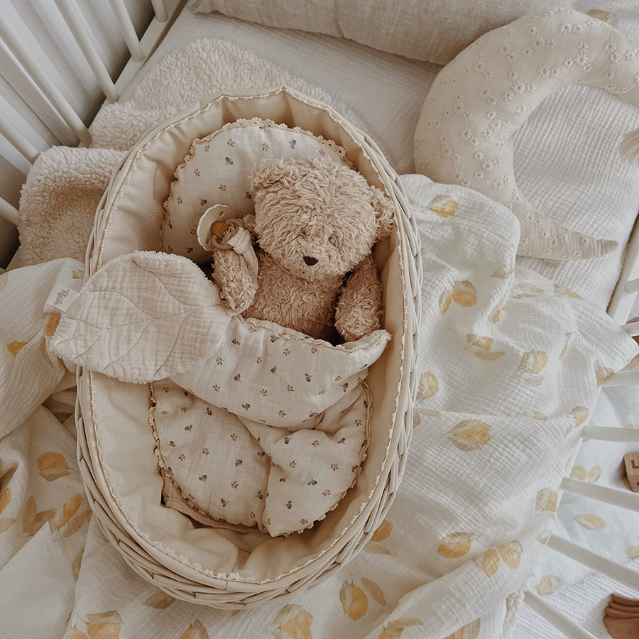 White wicker doll cradle with berry bedding